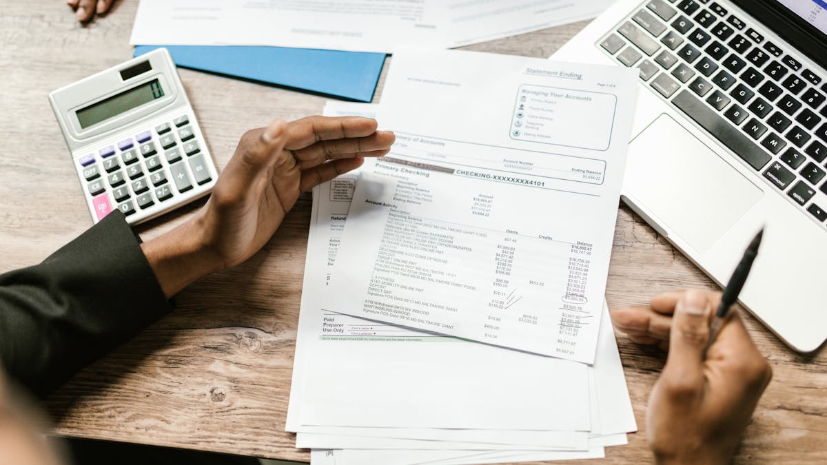 Financial documents, calculator, and laptop on an office desk — the document pack required when applying for a Hong Kong business bank account
