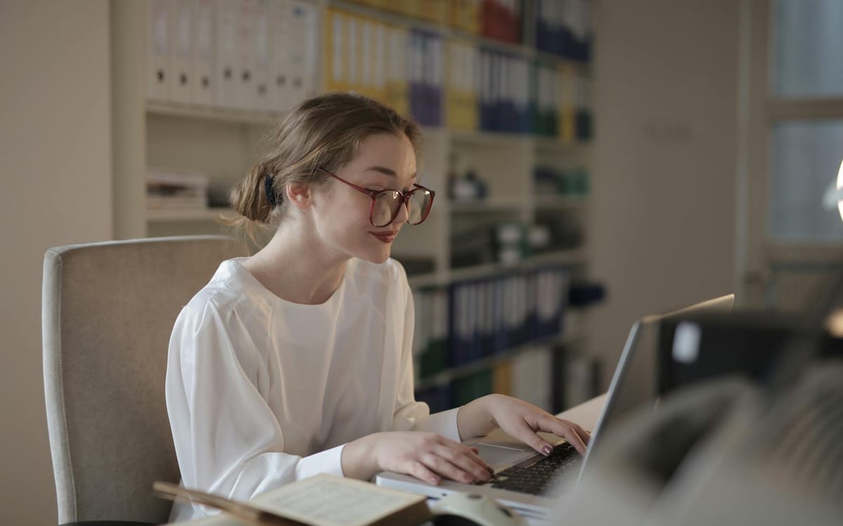 A focused professional working at a laptop in a bright, modern office — an independent consultant managing international clients