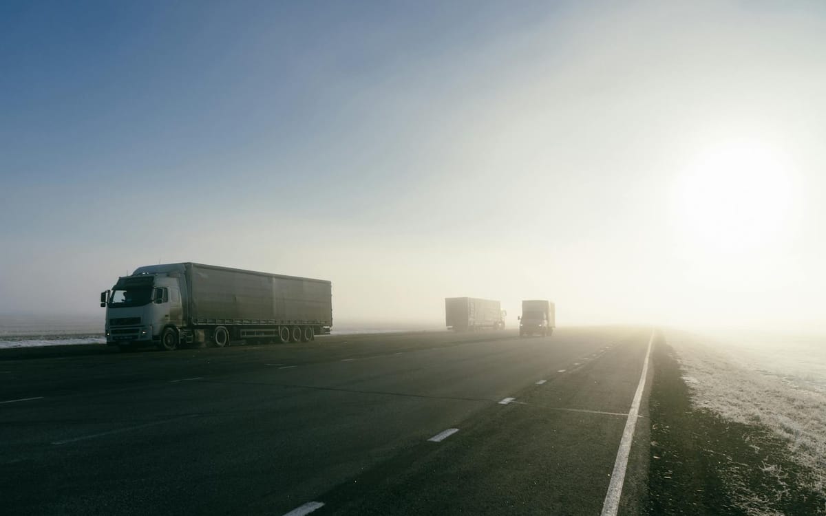 Des camions de fret sur une autoroute dégagée au lever du soleil — le maillon routier qui relie les usines de la Greater Bay Area aux ports de Hong Kong et à une chaîne d'approvisionnement transfrontalière