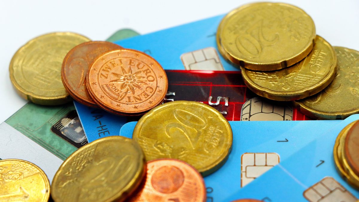 Des pièces de monnaie et des cartes bancaires à puce sur un bureau — les paiements quotidiens et les flux multi-devises que gère une société à Hong Kong
