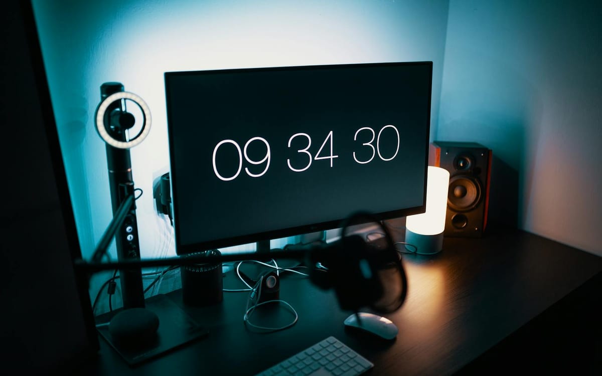 Le bureau d'un créateur, le soir — un écran, un petit anneau lumineux et des enceintes de studio éclairés par une lumière d'ambiance douce, le type d'installation à distance qui fait tourner une activité de cours