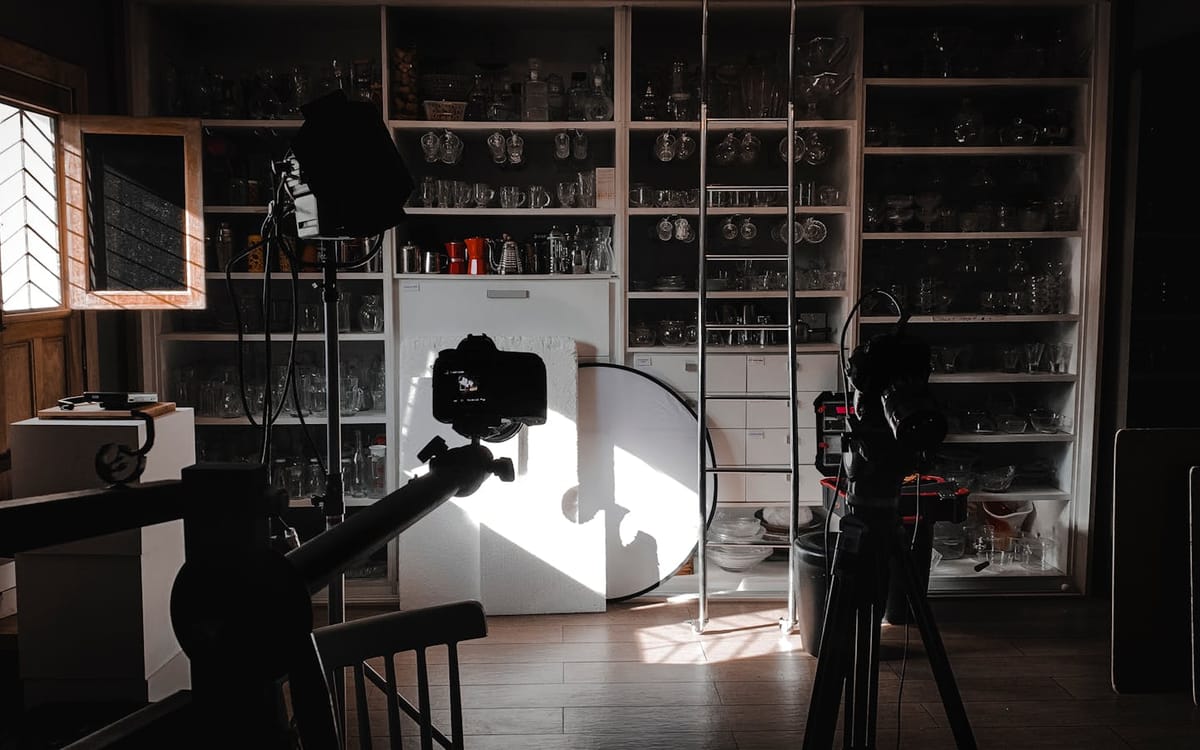 Un studio de tournage à domicile avec une caméra sur trépied, des softbox et un réflecteur prêts pour un tournage — le versant production d'une activité de contenu que la structure de société soutient