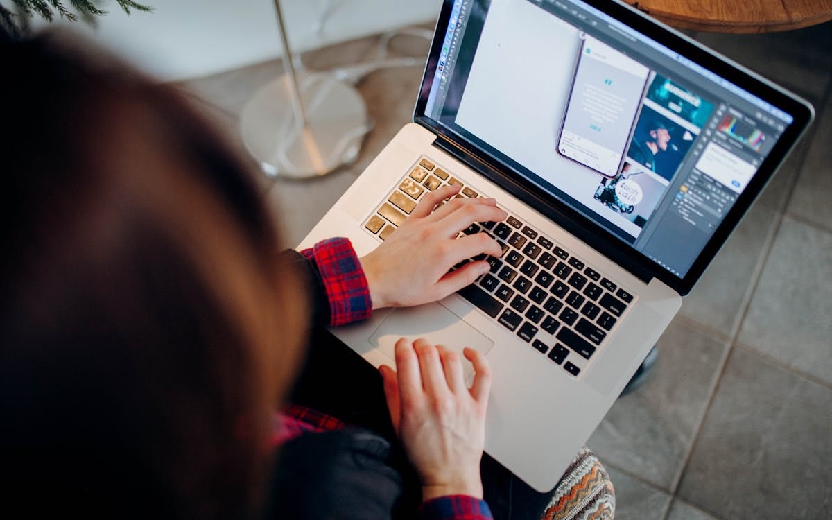 Vue par-dessus l'épaule d'une personne travaillant sur un ordinateur portable à un bureau — gérer une activité internationale à distance depuis un espace de travail à domicile