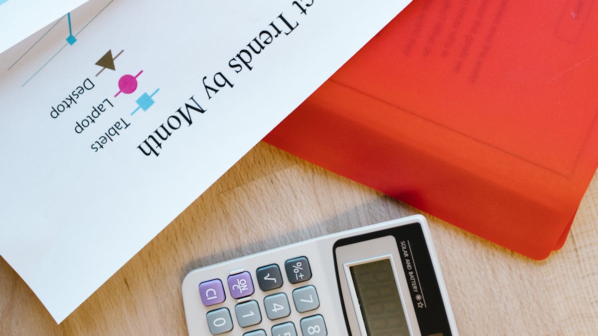 A business analytics chart of monthly trends beside a calculator on a desk — tracking the numbers behind a growing company
