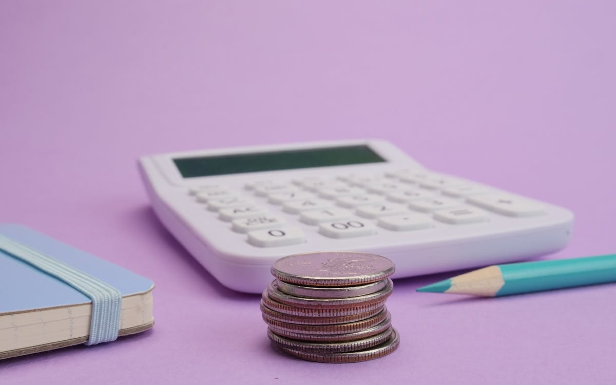 A small stack of coins beside a calculator and a notebook — budgeting the one-off and recurring costs of a Hong Kong company