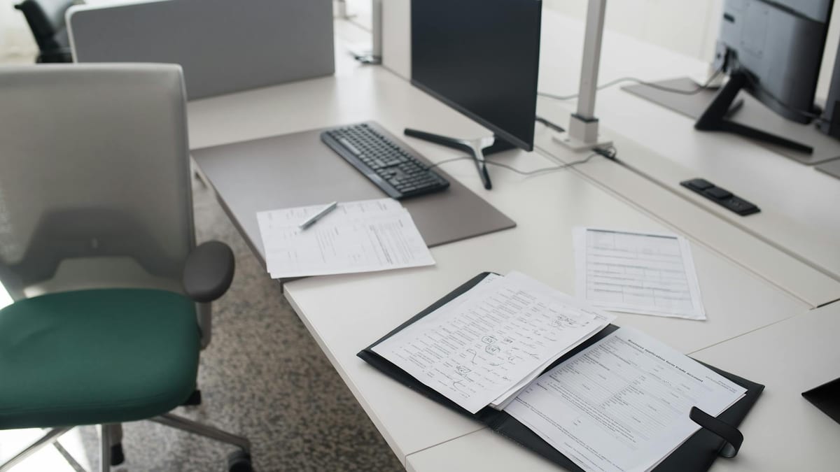A real working office desk with a monitor, keyboard, an open document folder and forms laid out — the everyday operations and organised records that demonstrate a company has genuine substance