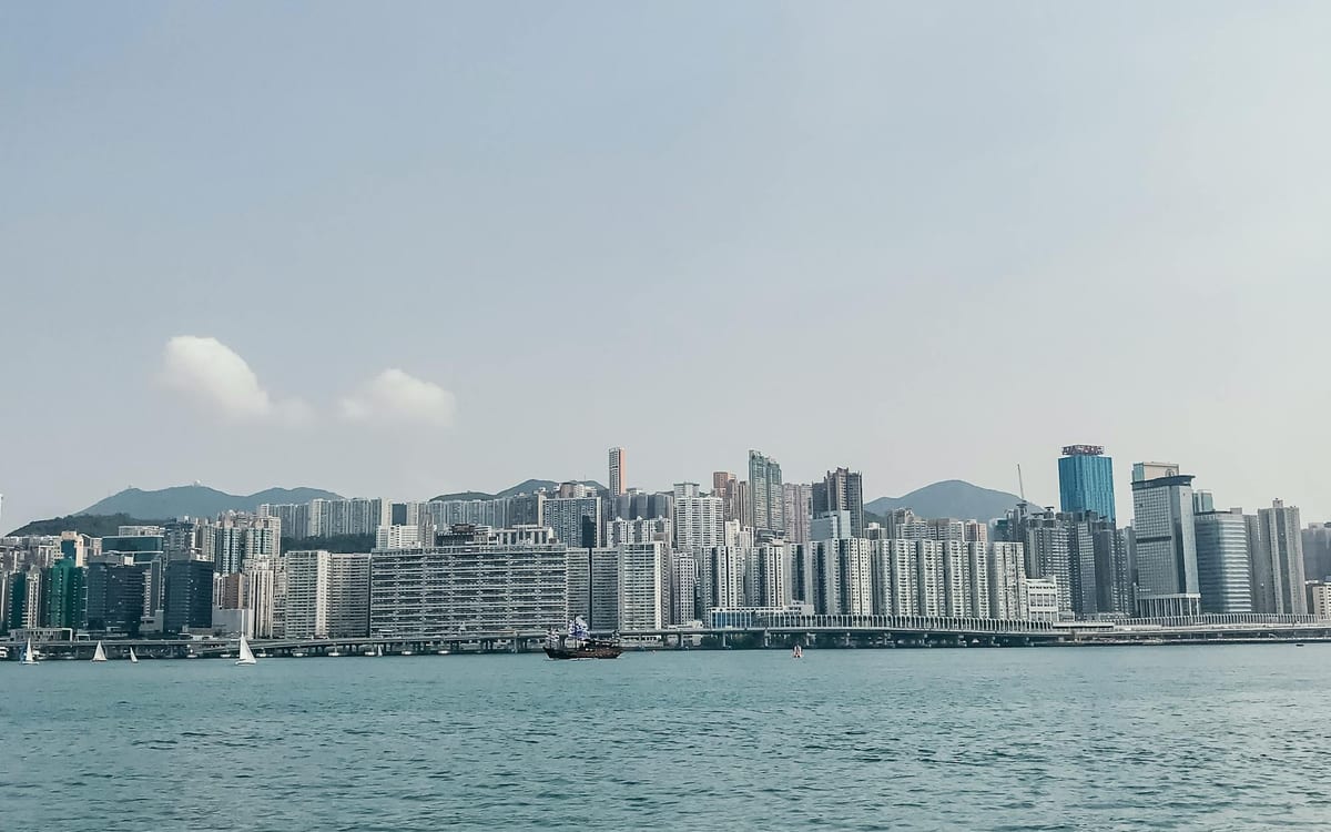 Hong Kong's harbourfront towers on a clear blue-sky day seen across calm water — the open, well-run environment a company operates in