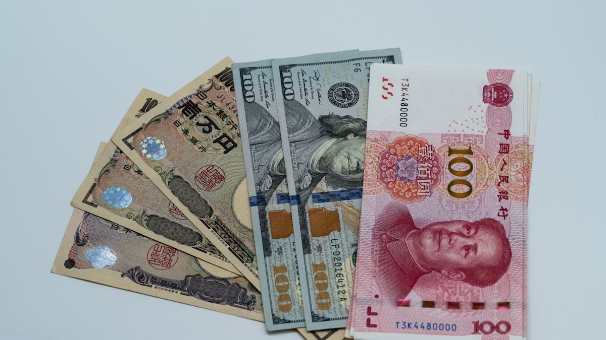 Billets de yen japonais, de dollars américains et de yuan chinois disposés sur une surface claire — la réalité multi-devises d'une société hongkongaise qui facture à l'international