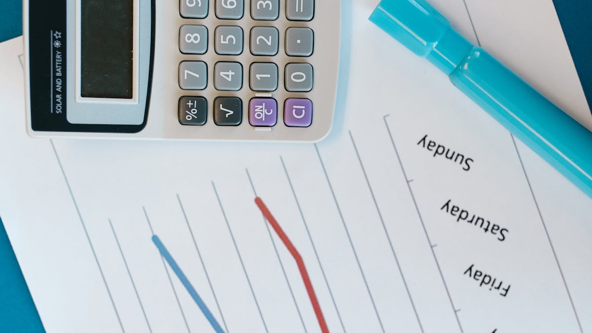 A calculator resting on a printed line chart — running the numbers on a Hong Kong company versus a UK limited company