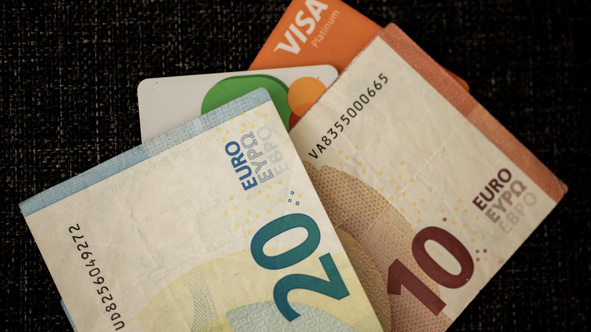 Euro banknotes tucked behind bank cards on a desk — the multi-currency banking a Hong Kong company gives an international founder